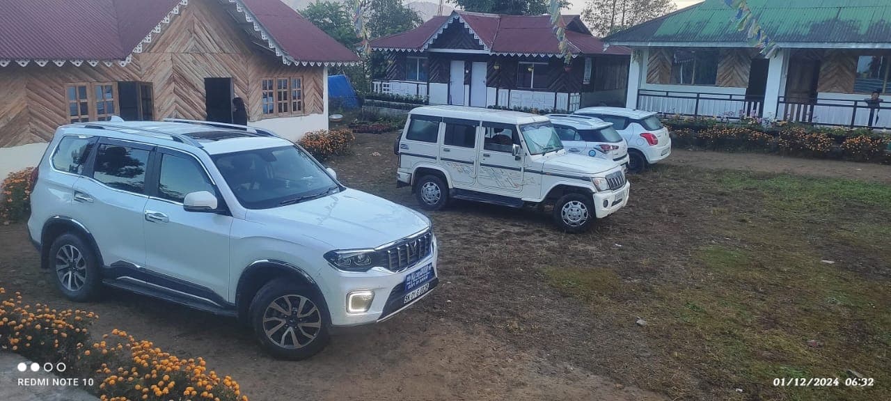 Wooden cottages with prayer flags and parked cars on arrival